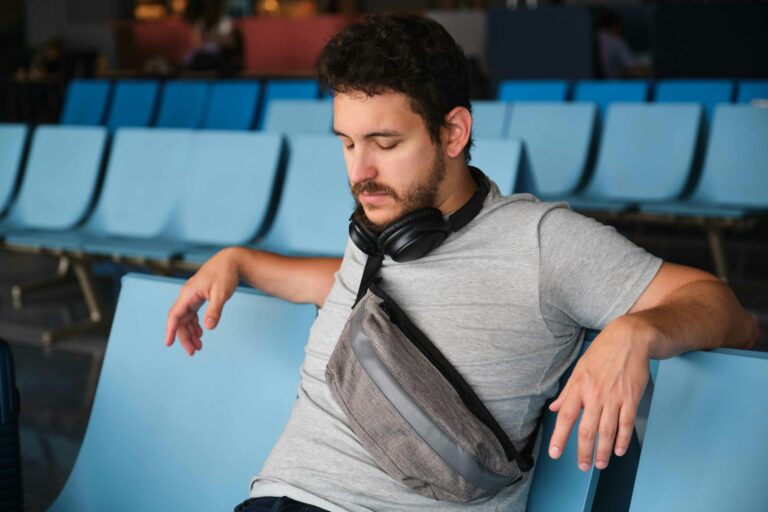 Man trying to sleep at the airport, sad because his flight was delayed.