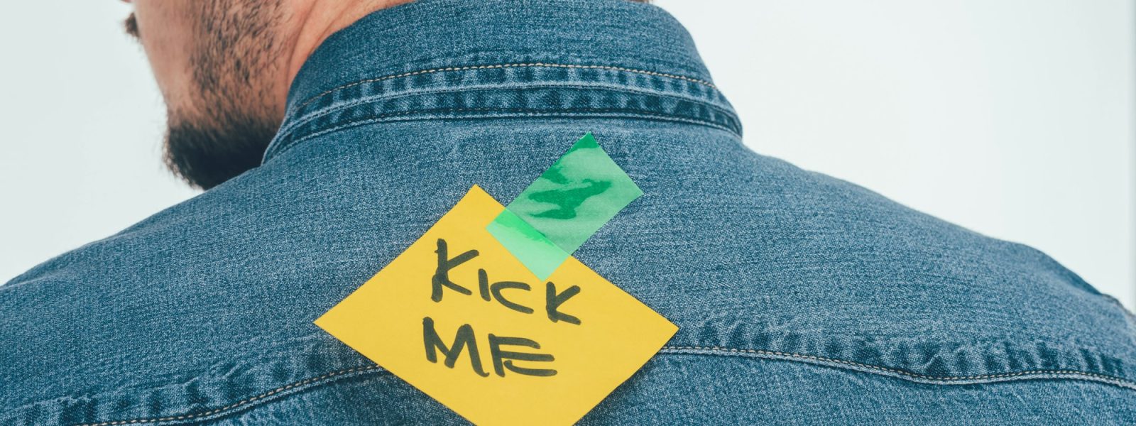 back view of man with note on sticky tape with kick me lettering on back, april fools day holiday