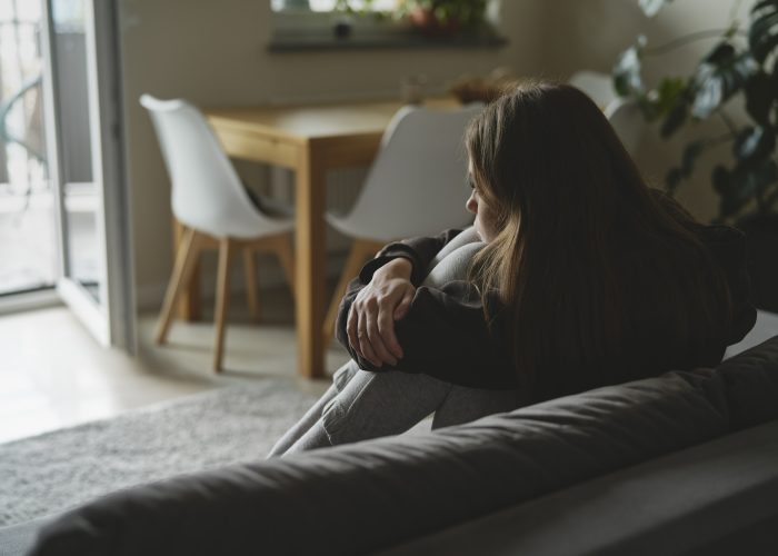 Caucasian sad woman sitting at the sofa with depression