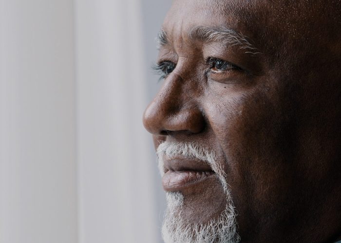 Close up pensive male old wrinkled face, 60s African bearded man deep in sad thoughts looking at