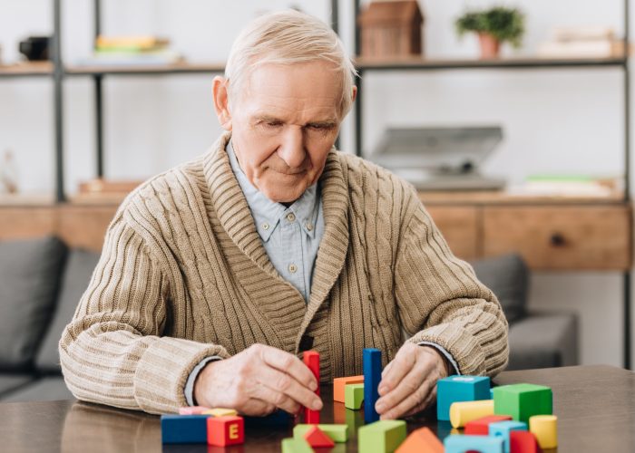 senior man playing with wooden toys at home